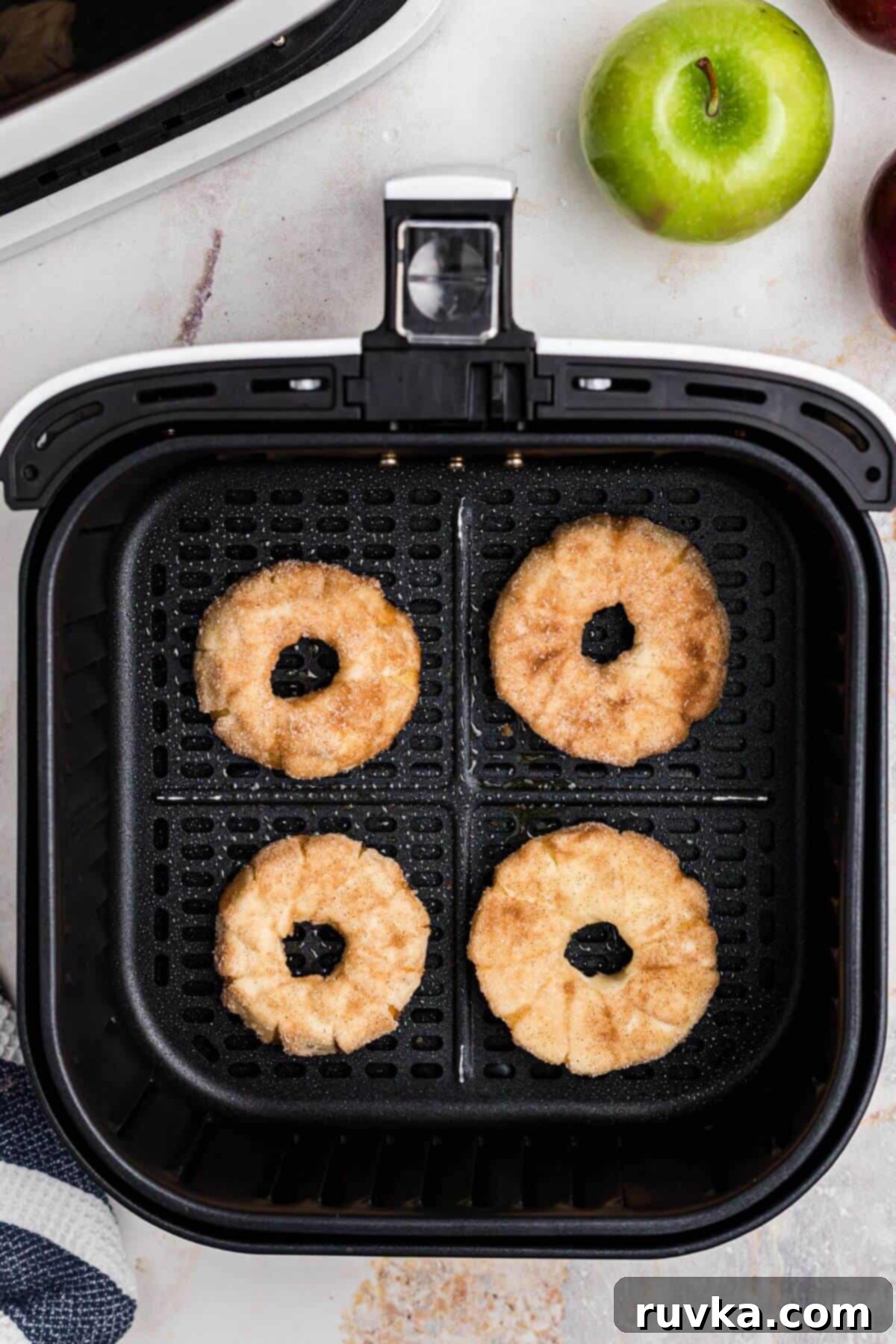 Flaky Air Fryer Apple Rings 9 Apple rings wrapped in pastry dough, in the air fryer basket before cooking.