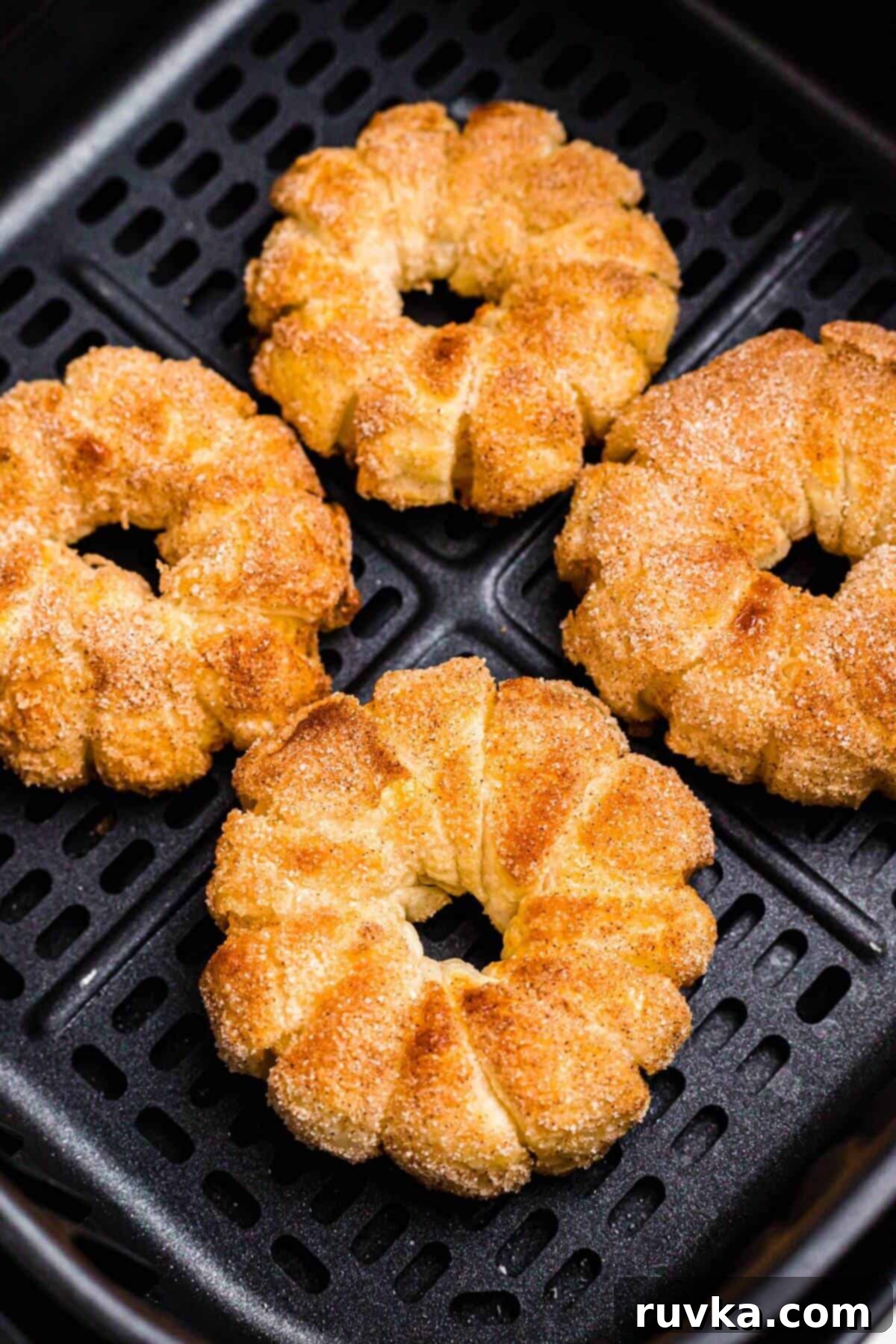 Flaky Air Fryer Apple Rings 10 Golden brown puff pastry wrapped apple rings in the air fryer basket after being cooked.