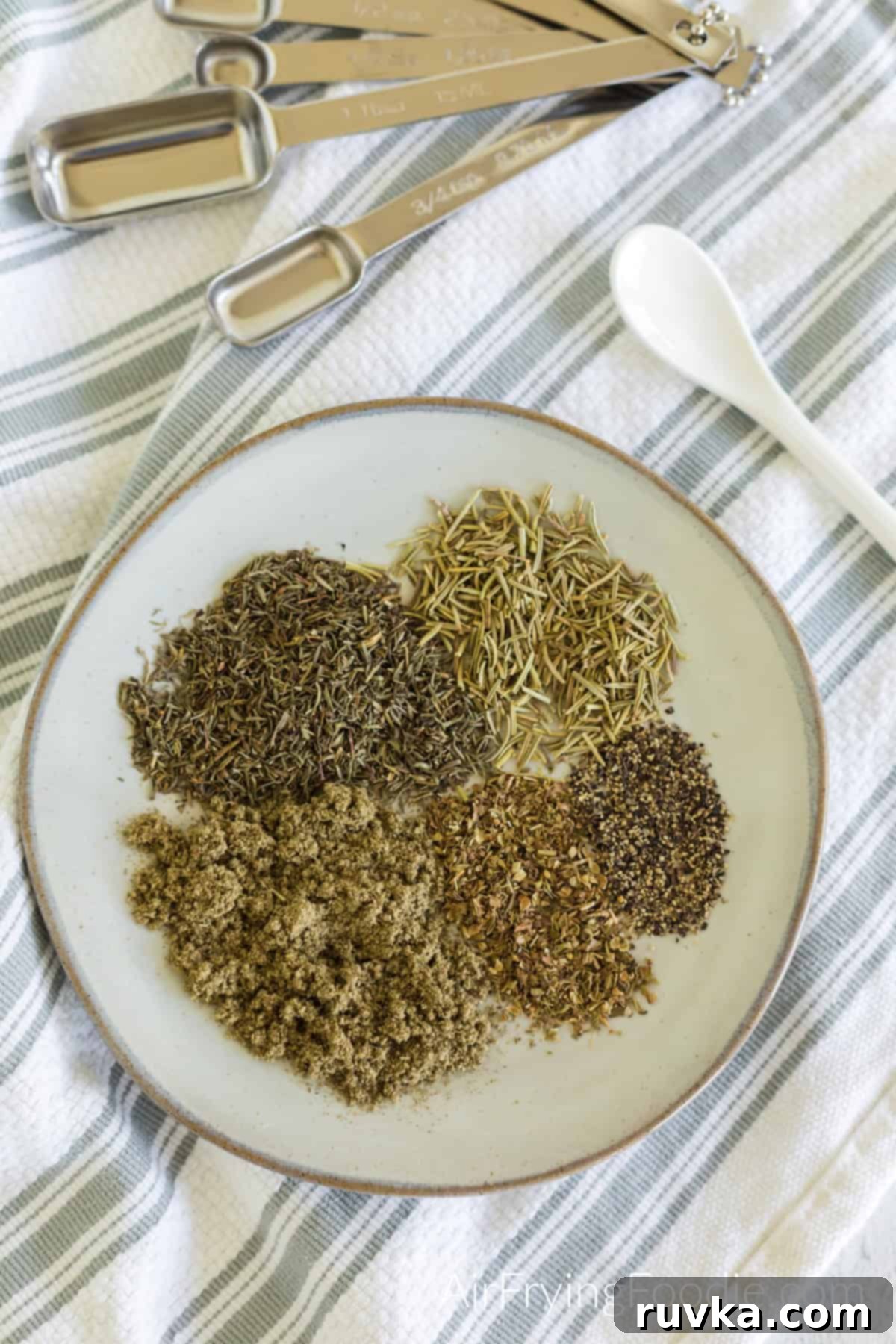 Flavorful Homemade Poultry Seasoning 3 Seasonings needed to make poultry seasoning measured out and added to a plate.
