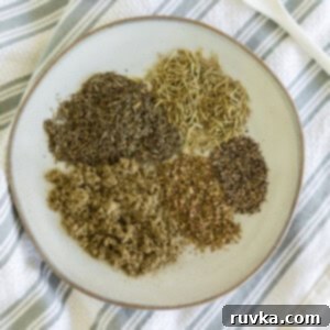 Flavorful Homemade Poultry Seasoning 5 Homemade poultry seasoning measured out in separate seasonings before being blended together. On a white plate.