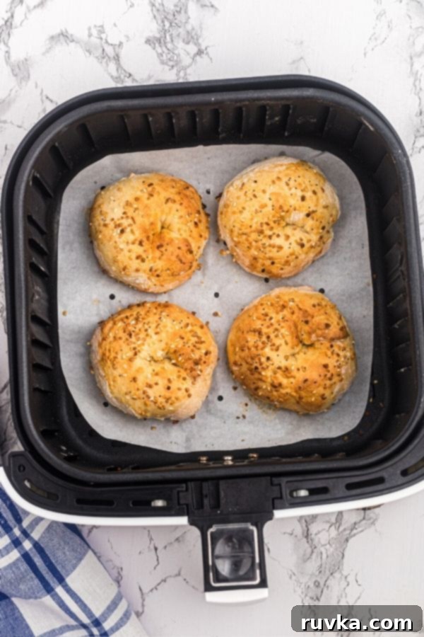 Easy Air Fryer Two-Ingredient Bagels 6 Golden bagels in the air fryer basket after being cooked.