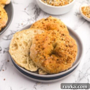 Easy Air Fryer Two-Ingredient Bagels 8 Golden bagels cut in half topped with seasonings and served on a light gray plate on a marble table.