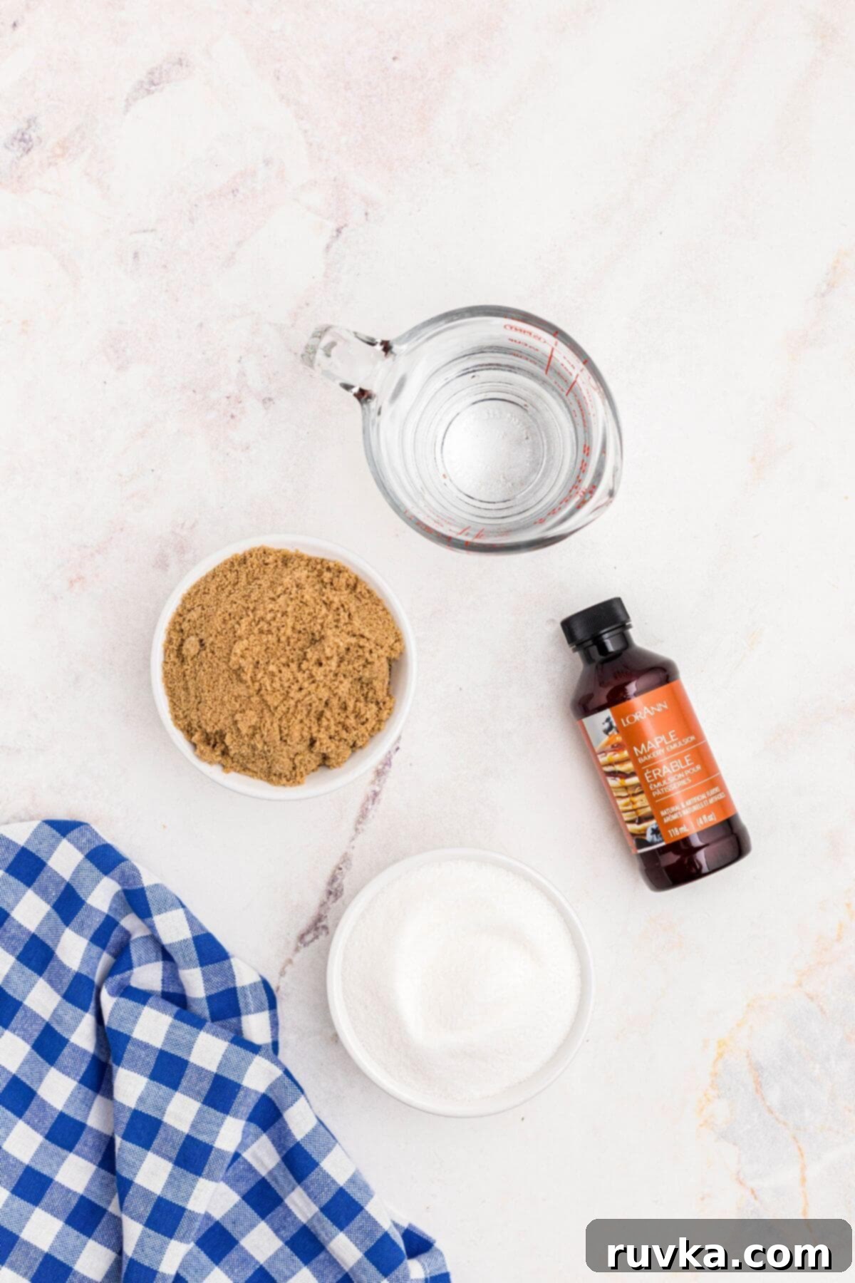 Easy Homemade Pancake Syrup 3 Sugar, brown sugar, water, and maple extract on a marble table.