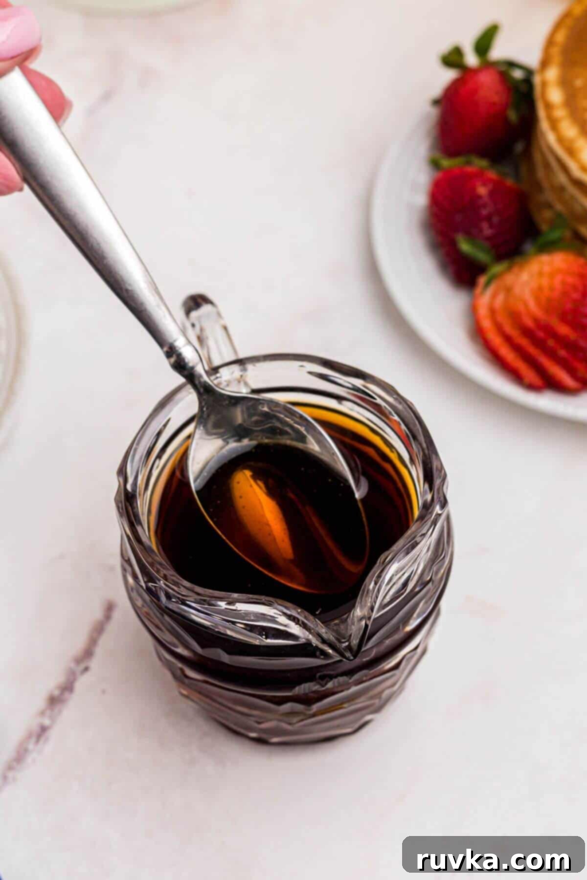 Easy Homemade Pancake Syrup 6 Freshly homemade syrup in a clear glass serving dish with a spoon lifting some syrup out.