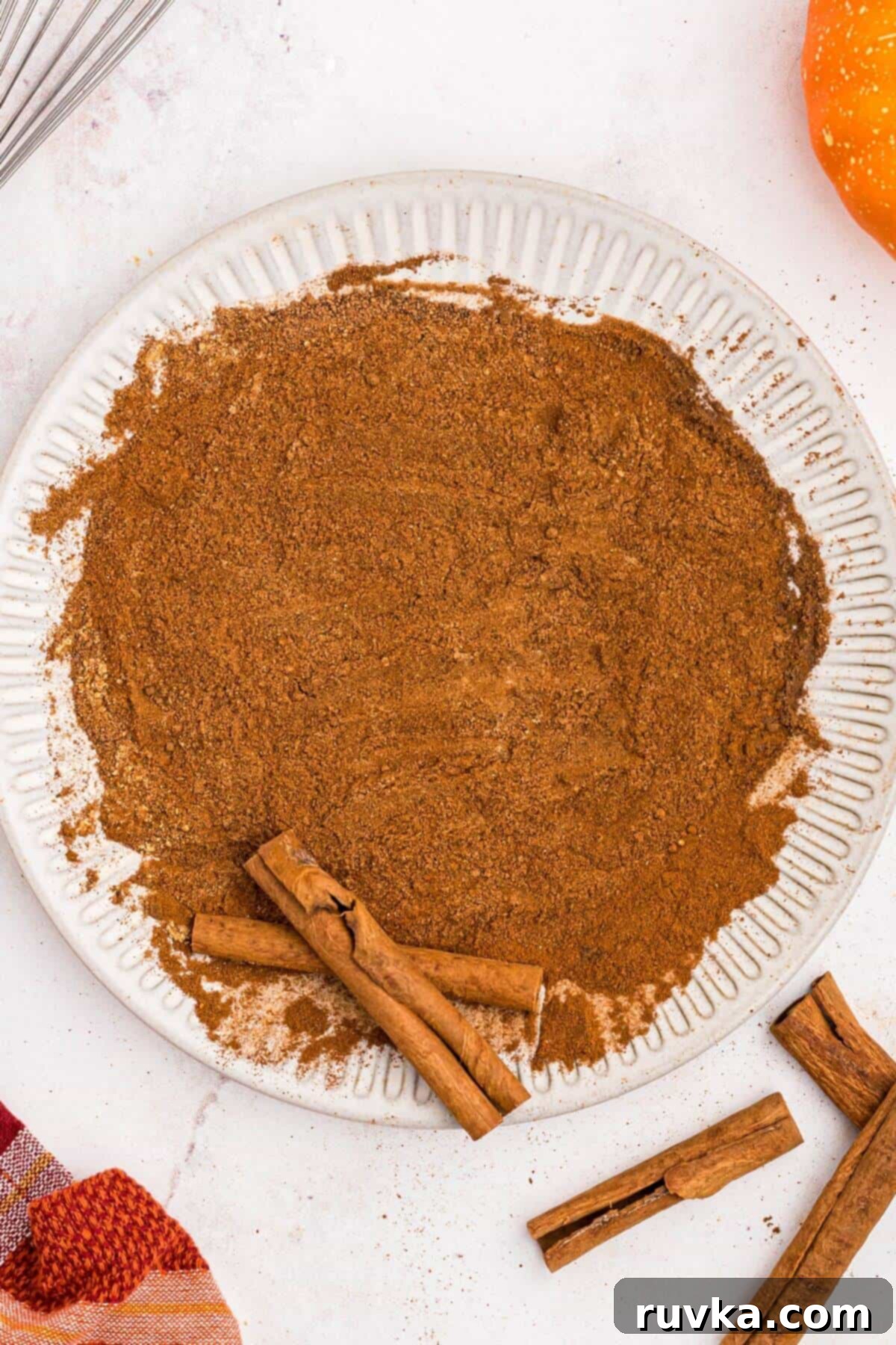 Autumn Spice Blend 4 Spices mixed together on a white plate with cinnamon sticks.