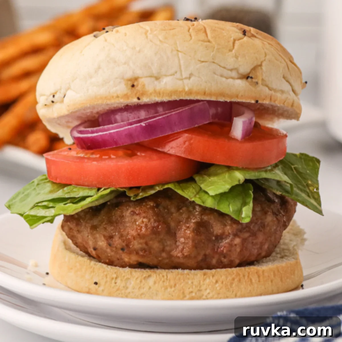 Elevate Your Burger Game: 5 Air Fryer Creations 4 An air fryer turkey burger patty nestled on a bun, complete with crisp lettuce, ripe tomato, and fresh onion slices.