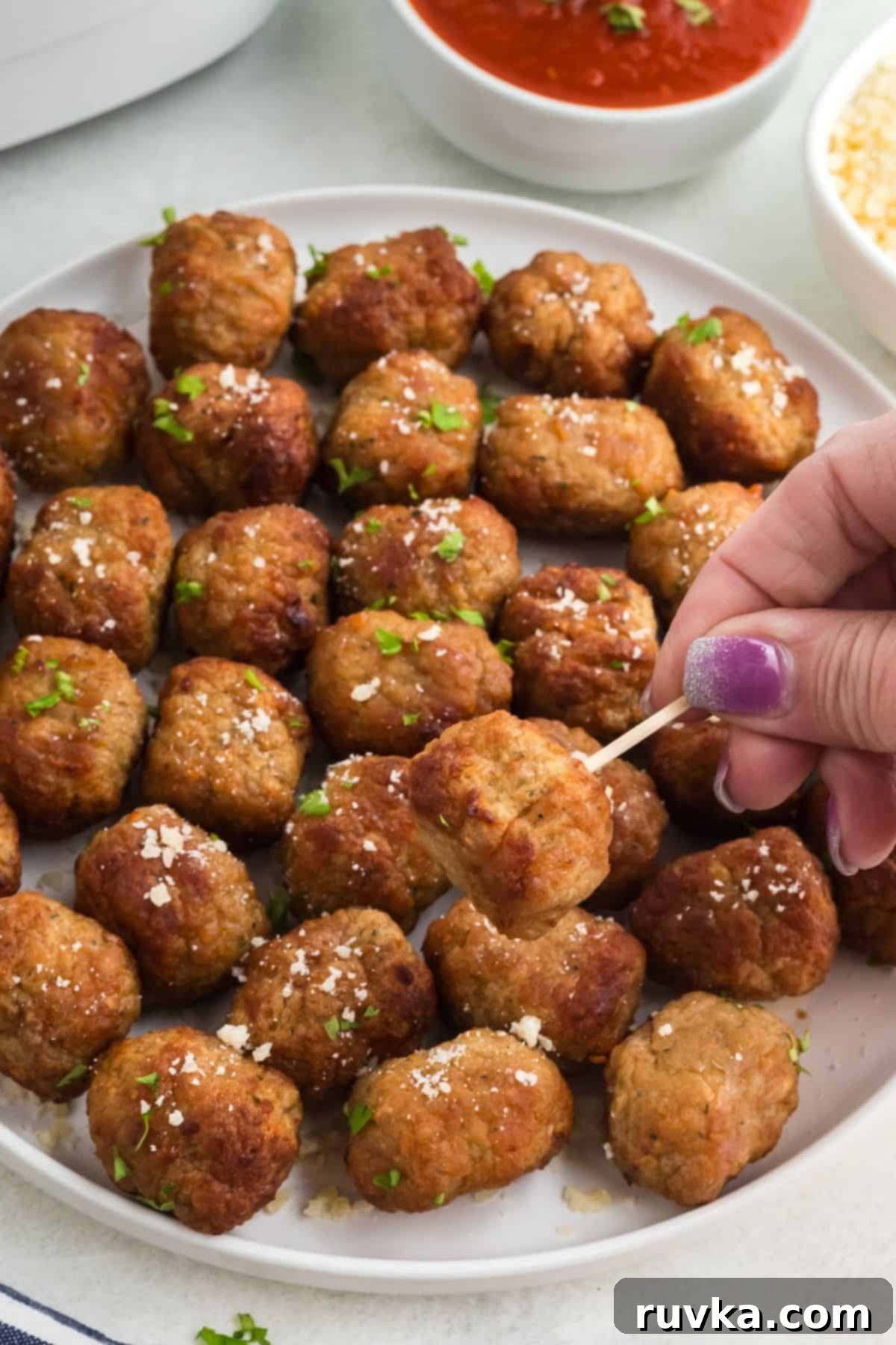 Quick Air Fryer Frozen Meatballs 3 Juicy golden brown meatballs on a white plate skewered with a toothpick.