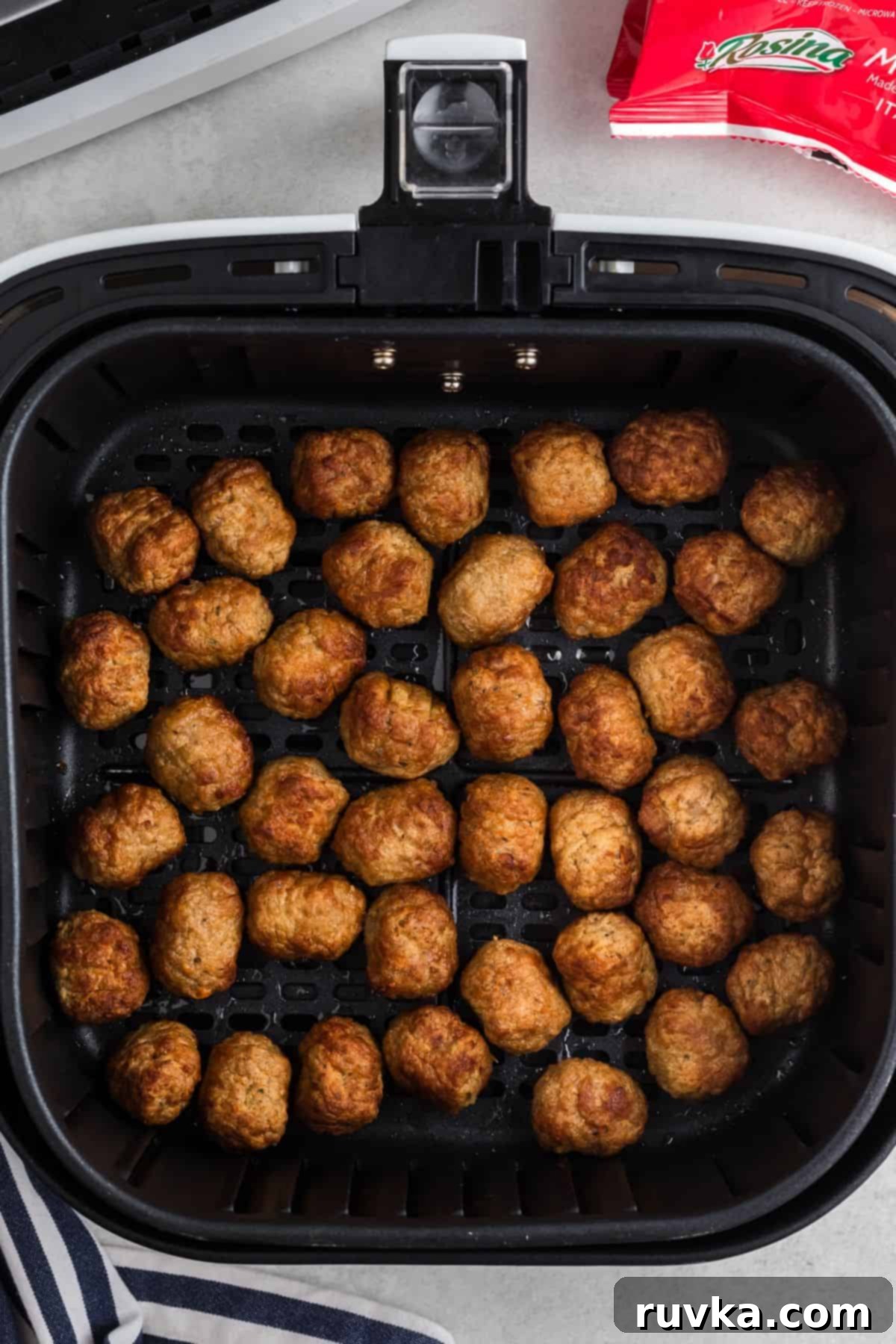 Quick Air Fryer Frozen Meatballs 5 Golden brown meatballs in the air fryer basket after being cooked.