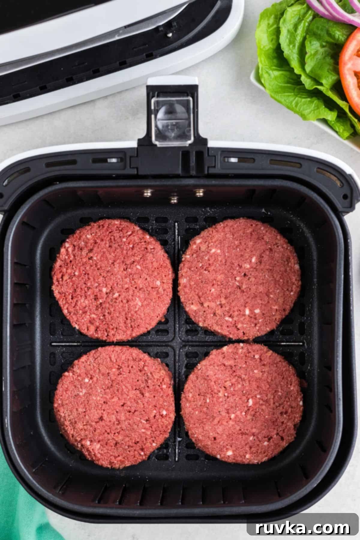Crispy Air Fryer Impossible Burgers 4 Two uncooked, frozen Impossible Burger patties placed neatly in a single layer inside an air fryer basket, ready to cook.