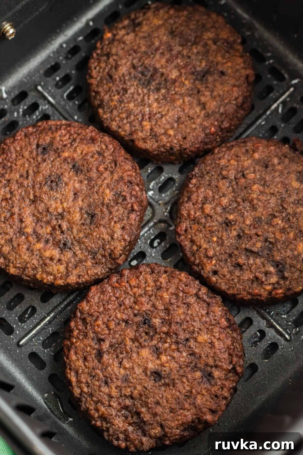 Crispy Air Fryer Impossible Burgers 5 Two perfectly cooked, golden-brown Impossible Burger patties fresh out of the air fryer, resting in the basket.