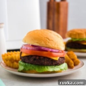 Crispy Air Fryer Impossible Burgers 6 Impossible burger in a bun with traditional burger toppings on a small plate with crispy fries.