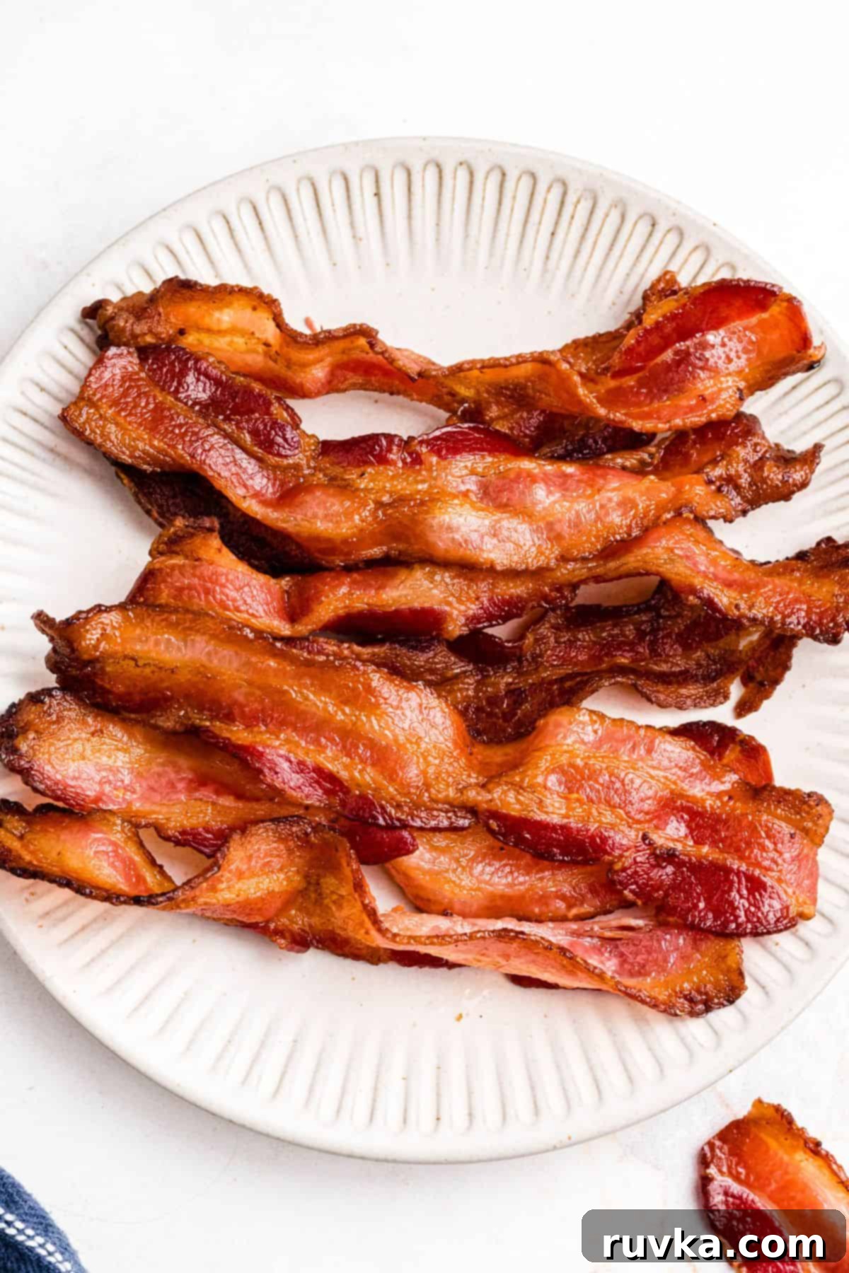 Air Fryer Frozen Bacon Hack 7 Golden crispy bacon on a cream plate.