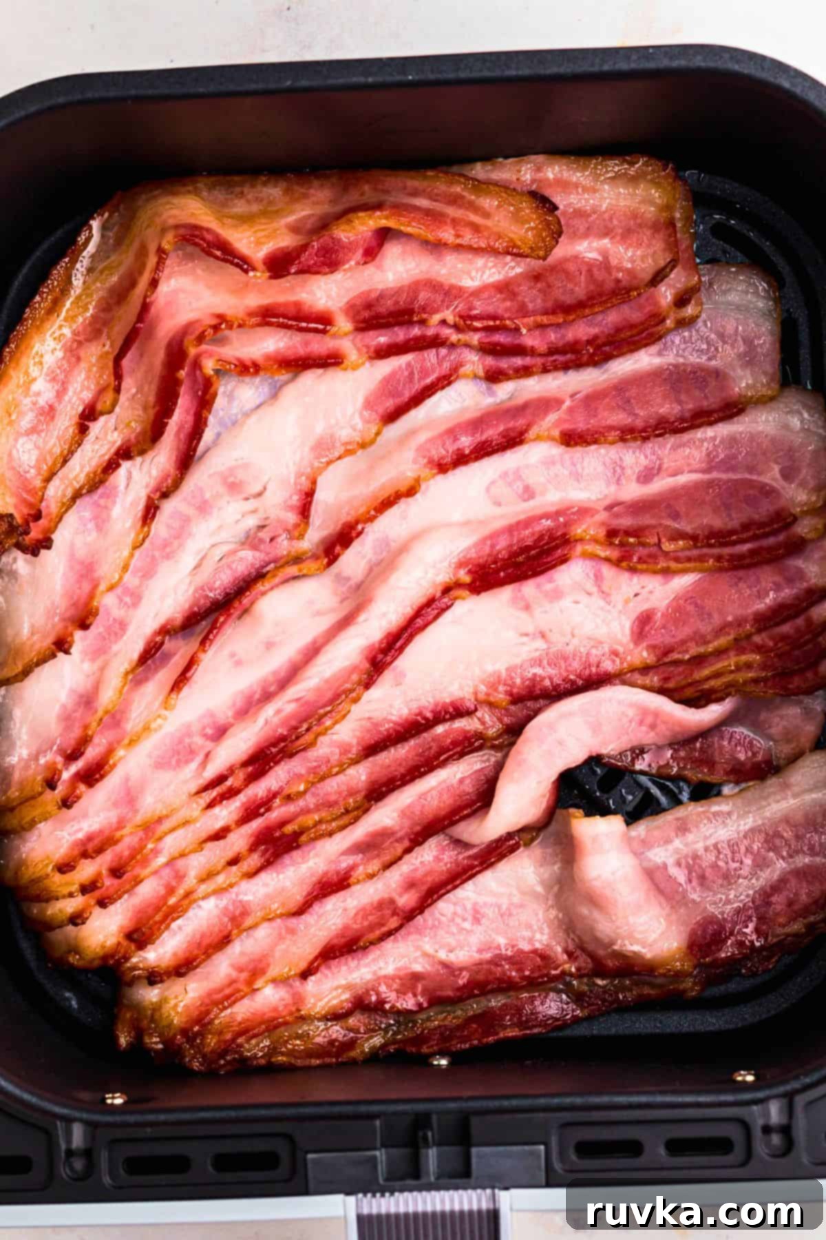 Air Fryer Frozen Bacon Hack 5 Uncooked thawed bacon in the air fryer basket after being separated during the air fryer cooking time.