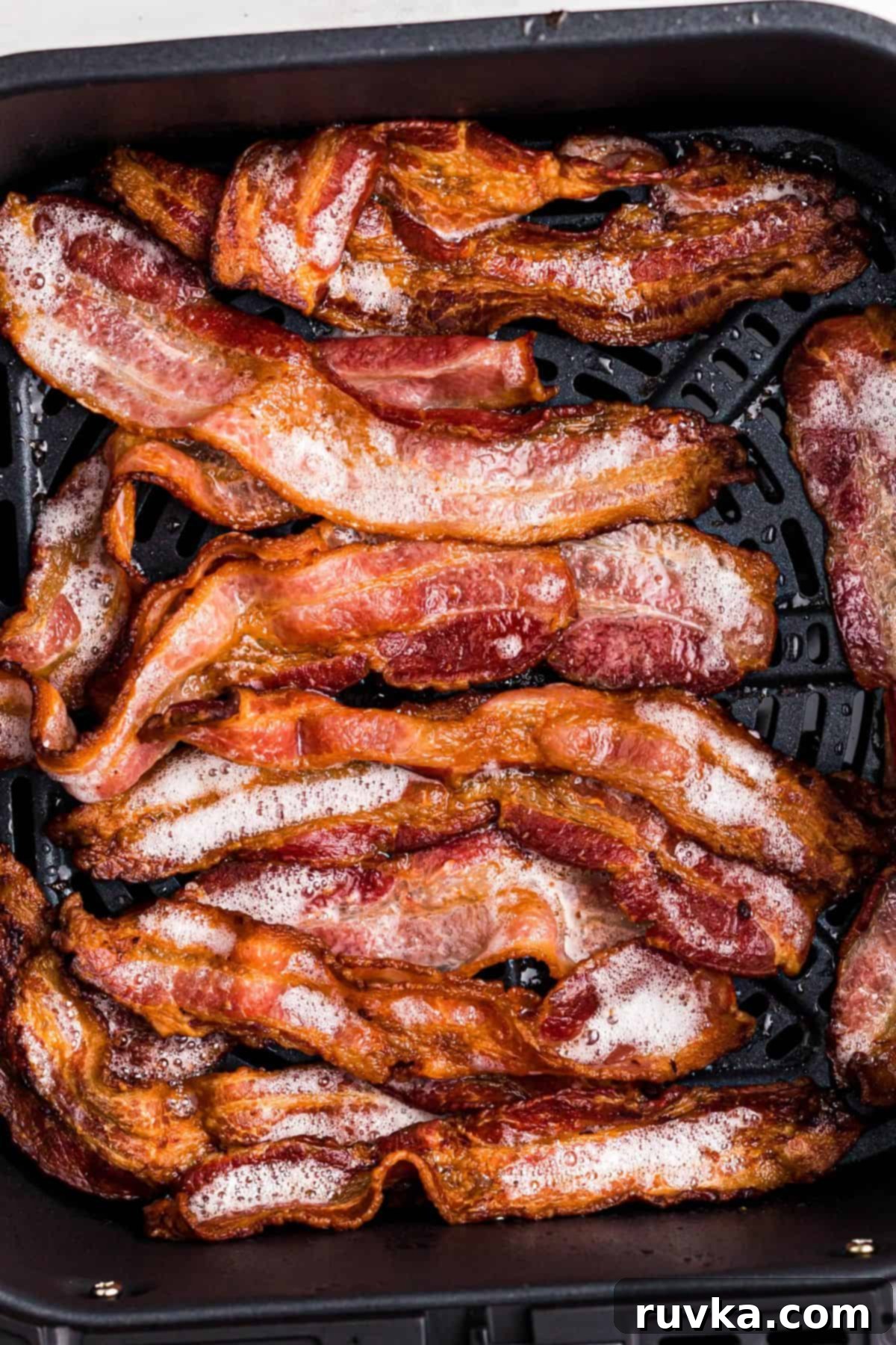 Air Fryer Frozen Bacon Hack 6 Golden crispy sizzling bacon in the air fryer basket after being cooked.