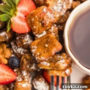 Crispy Air Fryer French Toast Bites 8 Golden French toast bites on a white plate with berries and syrup.