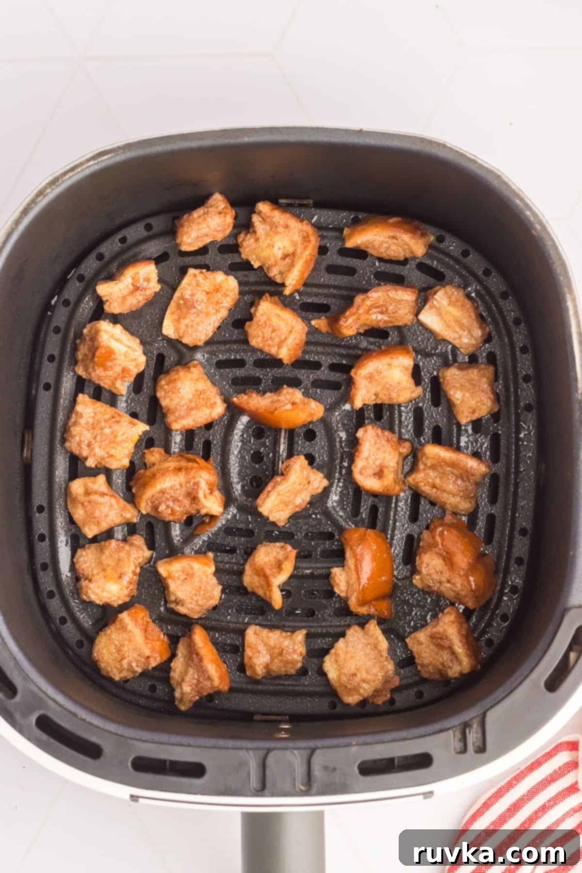 Crispy Air Fryer French Toast Bites 4 French toast bites in the air fryer basket before cooking.