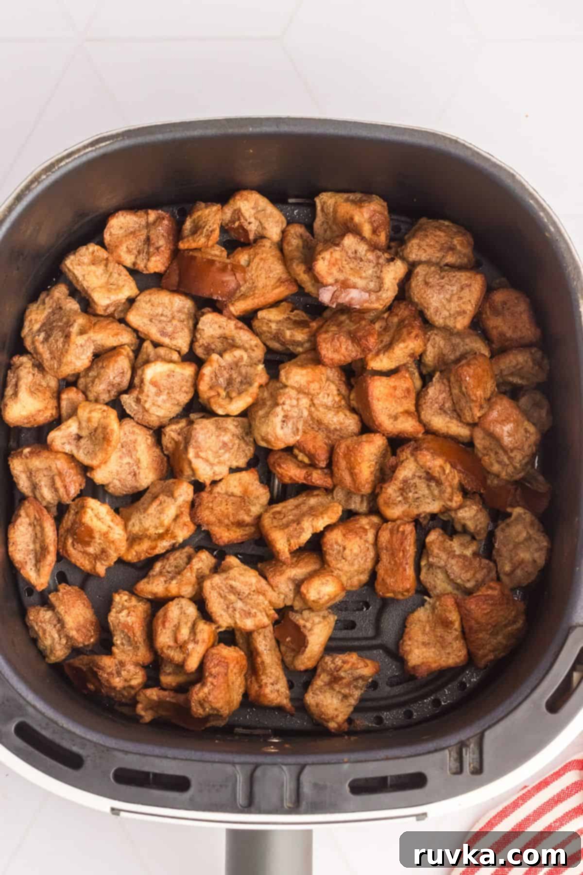 Crispy Air Fryer French Toast Bites 5 Golden French toast bites in the air fryer basket after cooking.