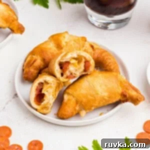 Air Fryer Pizza Crescent Bites 9 Pizza crescent rolls stacked on a small white plate with cheese and pepperoni inside.
