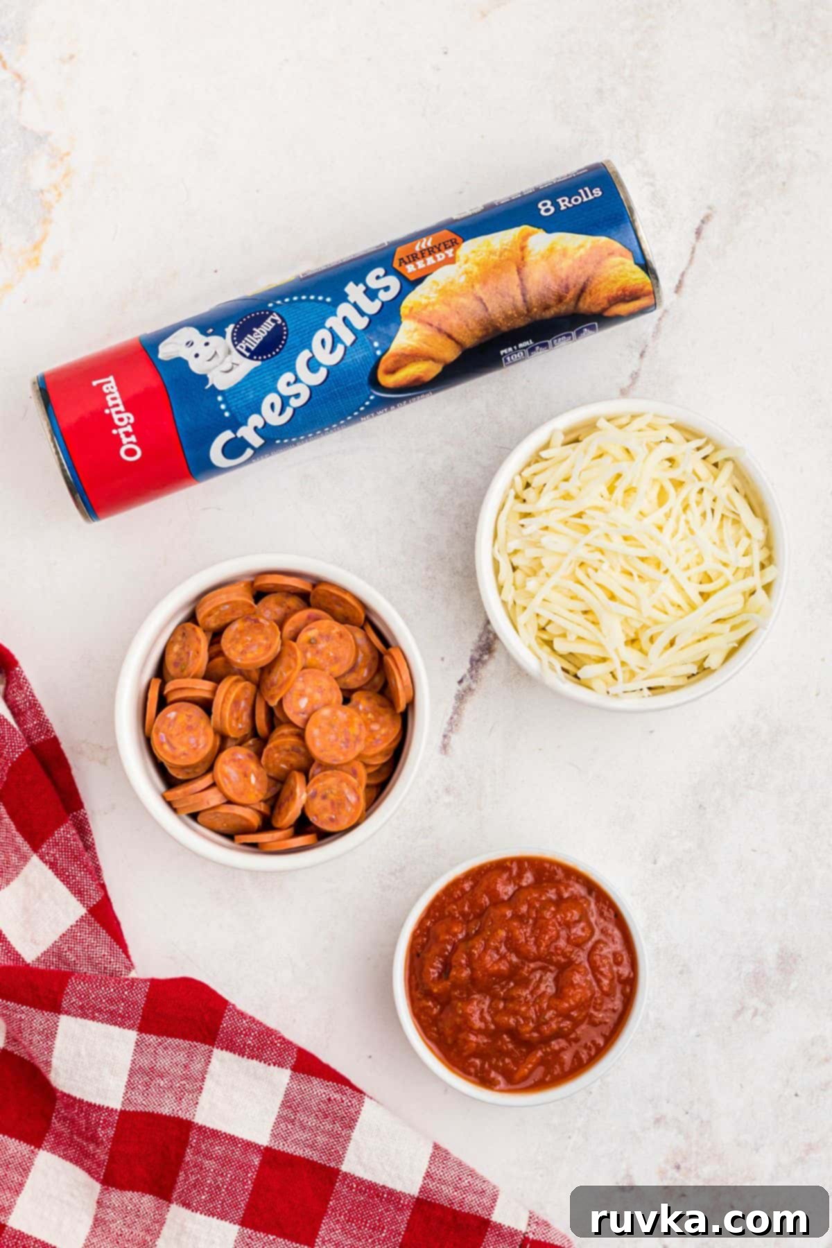 Air Fryer Pizza Crescent Bites 3 Can of crescent roll dough with small bowls of pepperoni, shredded mozzarella cheese, and pizza sauce, ready for making pizza crescent rolls.