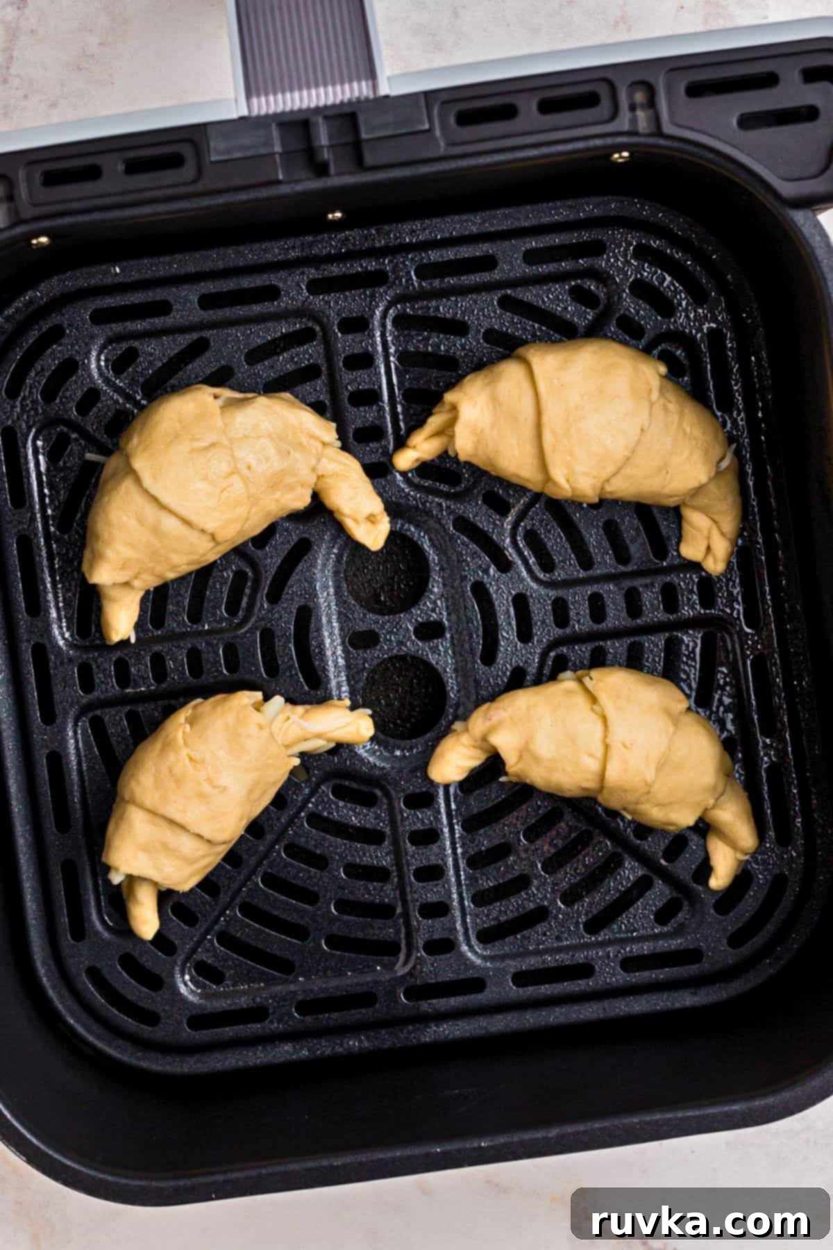 Air Fryer Pizza Crescent Bites 5 Filled crescent roll dough in the center of the air fryer basket before being cooked.