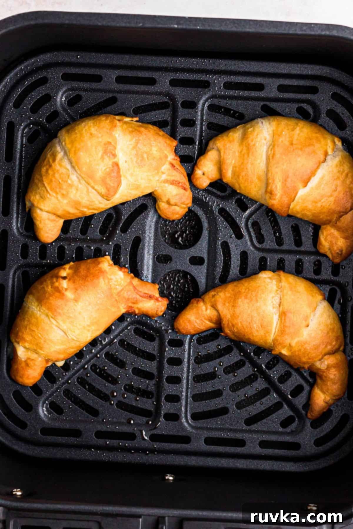 Air Fryer Pizza Crescent Bites 6 Golden crescent rolls filled with pizza toppings, in the air fryer basket after being cooked, looking crispy and delicious.