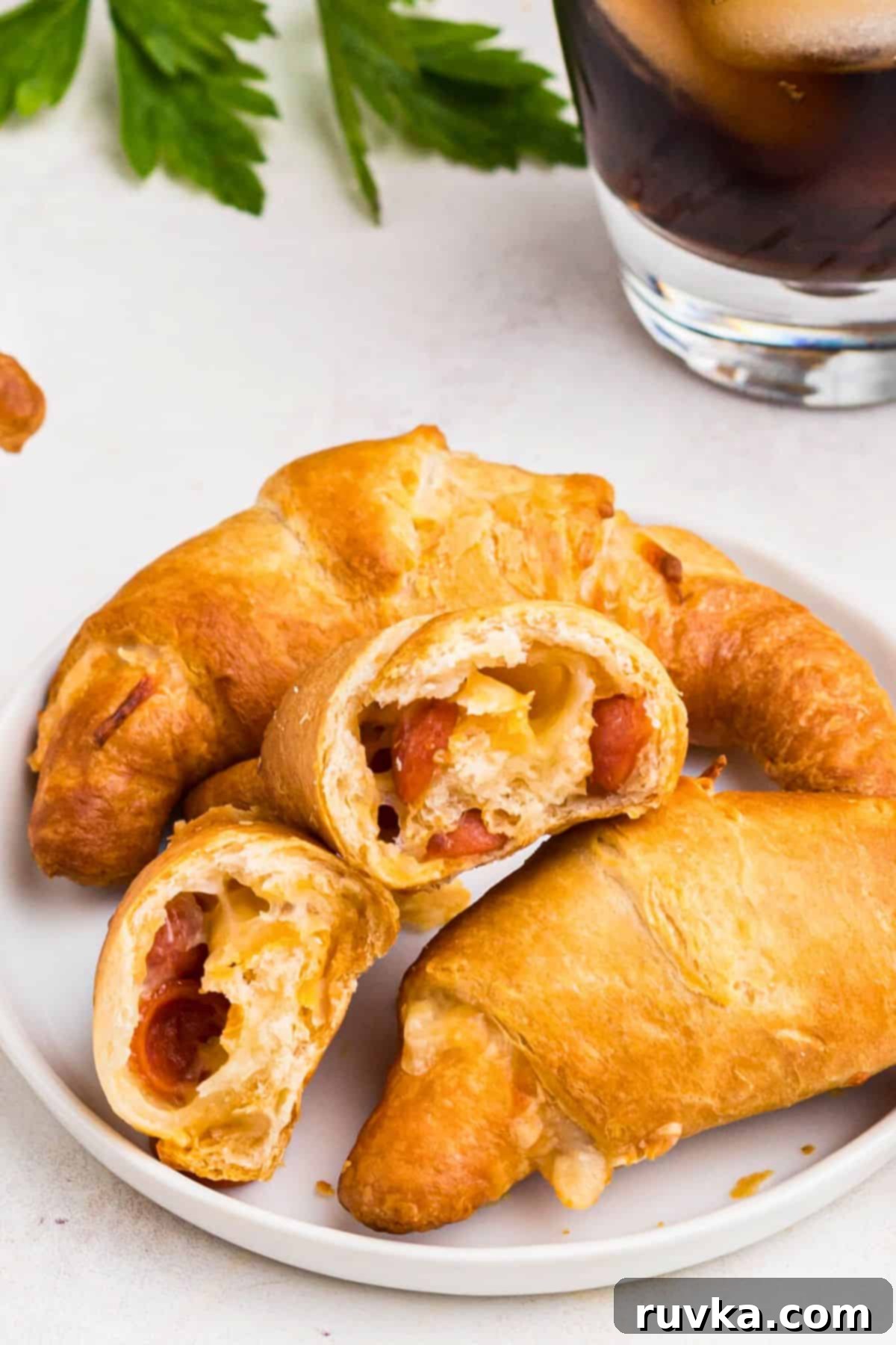 Air Fryer Pizza Crescent Bites 7 Golden pizza crescent rolls on a small white plate with melted cheese and small pepperoni showing.