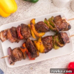 Point-Friendly Air Fryer Dishes 6 Steak kabobs with vegetables on a white plate with bell peppers scattered on the table.