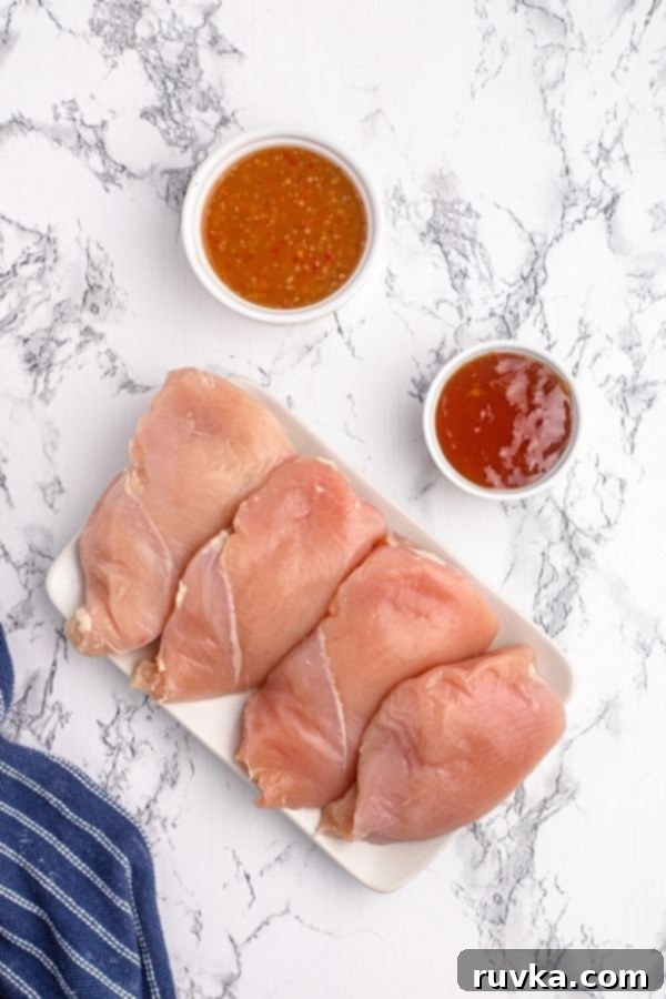 Golden Peach Air Fryer Chicken 4 Ingredients to make glazed chicken on a white plate. Raw chicken, Italian dressing, and peach preserves.