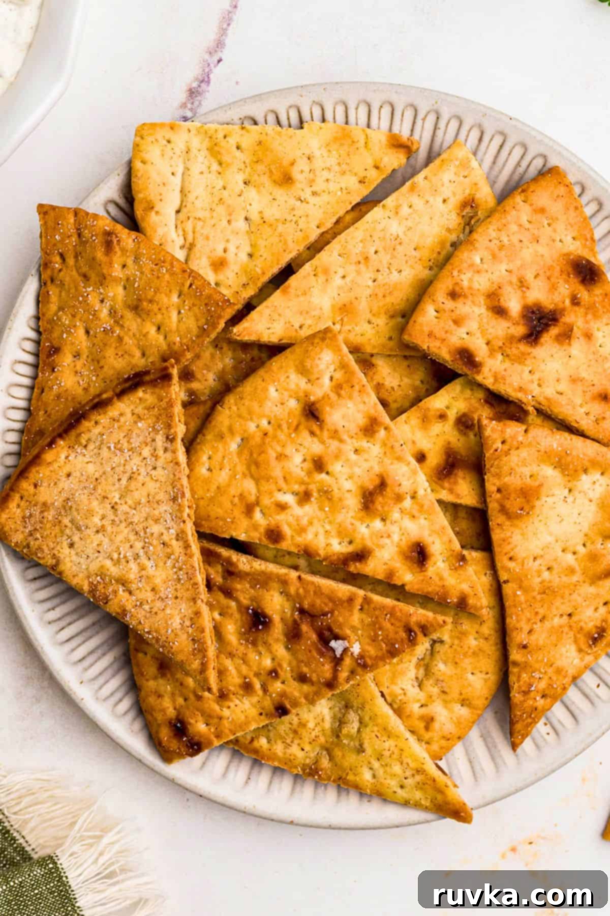 Crispy Air Fryer Pita Chips 2 Crispy golden chips on a white plate in front of an air fryer.