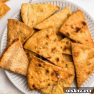 Crispy Air Fryer Pita Chips 7 Crispy golden chips on a white plate in front of an air fryer.