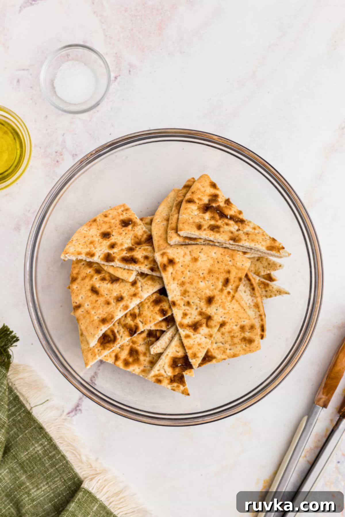 Crispy Air Fryer Pita Chips 3 Pita bread cut into triangles, tossed with olive oil and salt in a clear glass bowl.