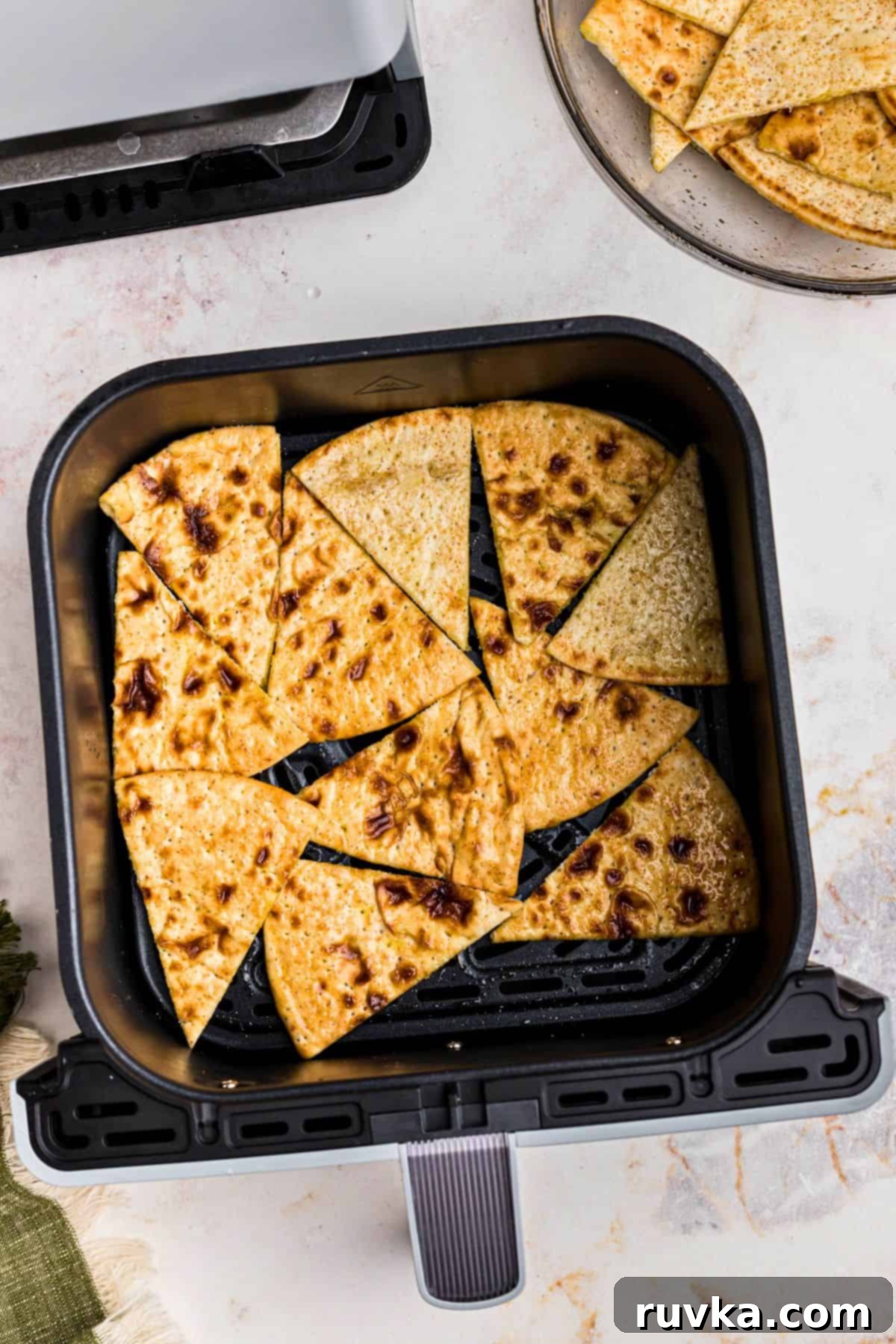 Crispy Air Fryer Pita Chips 4 Pieces of pita bread in the air fryer basket before being cooked into chips.