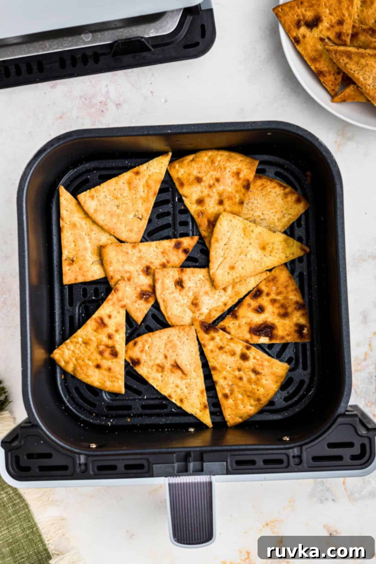 Crispy Air Fryer Pita Chips 5 Crispy golden brown pita chips in the air fryer basket after being cooked.