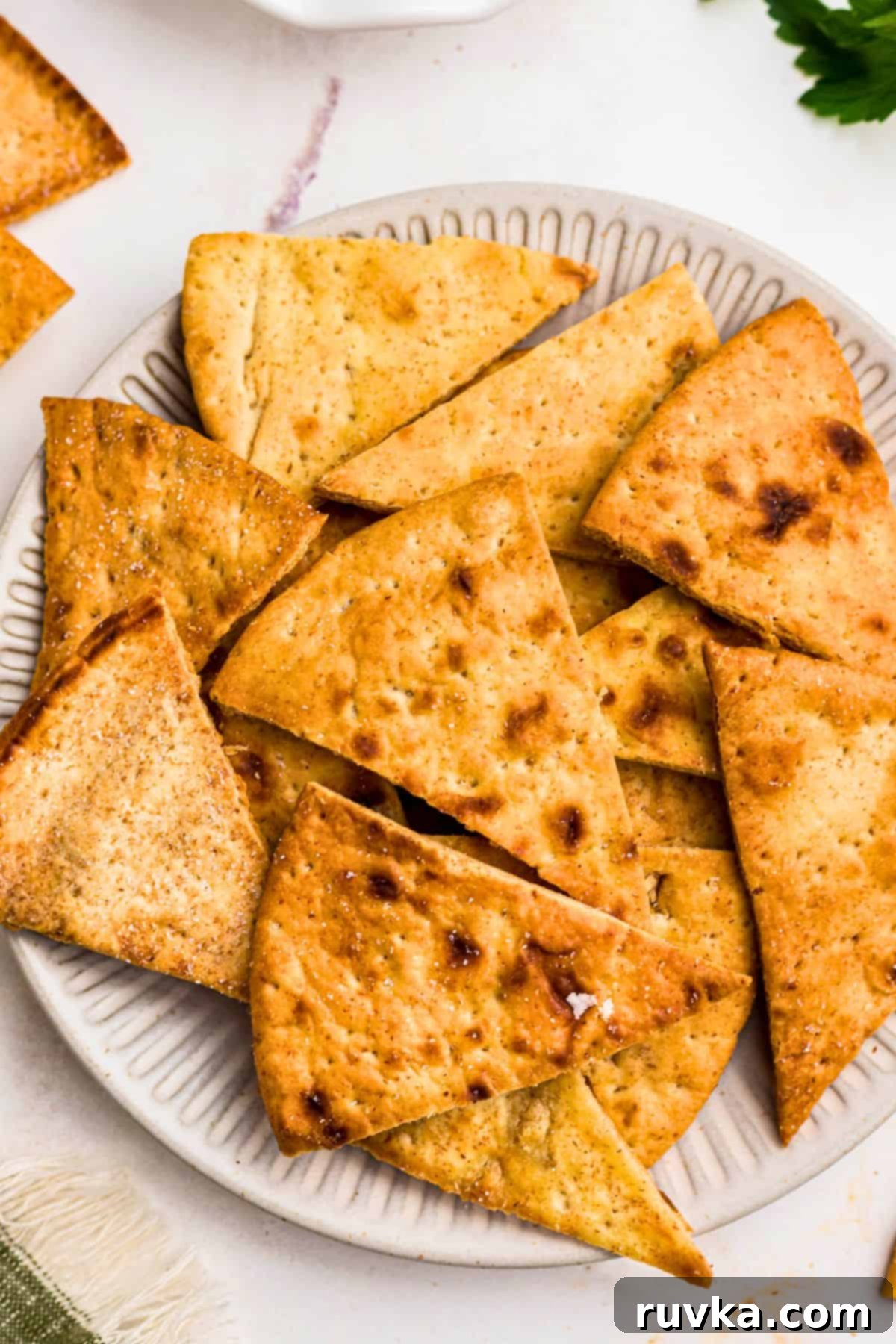Crispy Air Fryer Pita Chips 6 Crispy golden chips on a white plate in front of an air fryer.