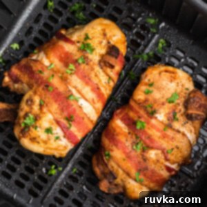 Keto Air Fryer Delights 8 Bacon wrapped chicken breasts in the air fryer basket, cooking to crispy perfection for a keto dinner.