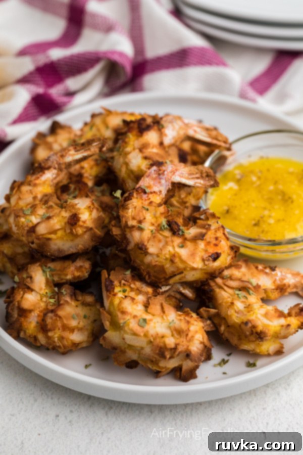 Crispy Air Fryer Keto Coconut Shrimp 2 golden brown keto Coconut shrimp made in the air fryer on a white plate