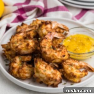 Crispy Air Fryer Keto Coconut Shrimp 11 Air Fryer Keto Coconut Shrimp on a white plate ready to eat with a side of buttery dipping sauce to serve.
