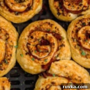 Crispy Air Fryer Pesto Pinwheels 8 Golden flaky stuffed pinwheels cooking in the air fryer basket.