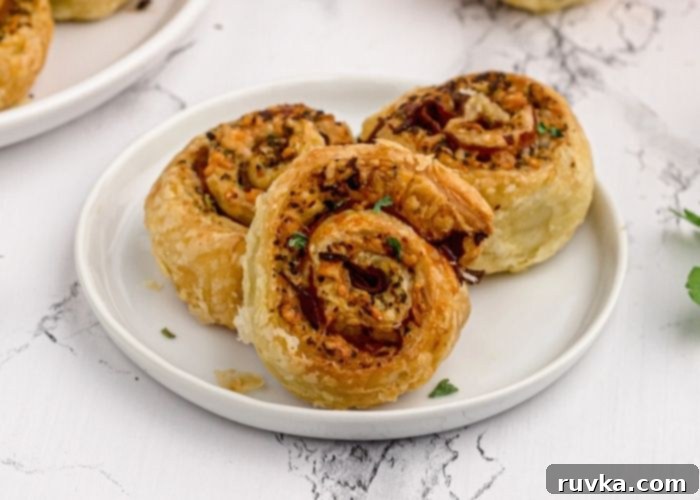 Crispy Air Fryer Pesto Pinwheels 7 Close-up of a single golden Air Fryer Pesto Pinwheel on a white plate, garnished with fresh parsley flakes, ready to be enjoyed.
