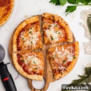 Crispy Air Fryer Pita Pizza 8 Cheesy pizza with a golden crust of pita bread on a cutting board on a marble table.