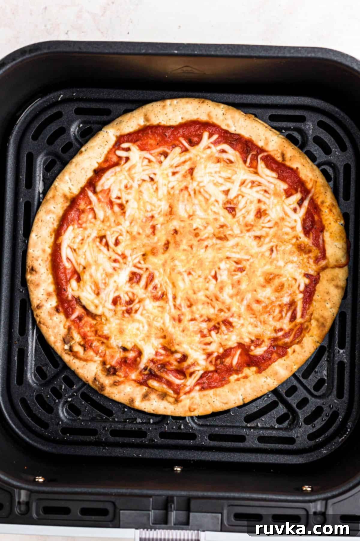 Crispy Air Fryer Pita Pizza 6 Crispy pita pizza with golden brown crust in the air fryer basket.