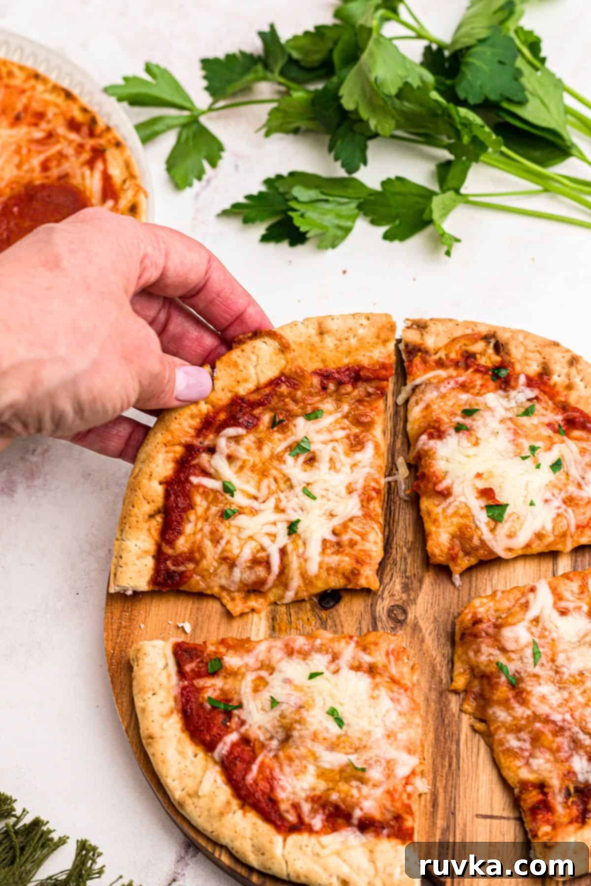 Crispy Air Fryer Pita Pizza 7 Slice of pita pizza being lifted off of cutting board on a marble table.