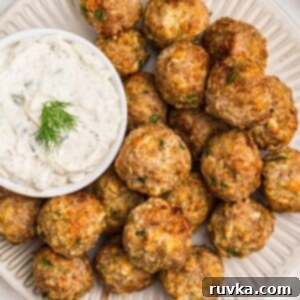 Crispy Air-Fried Greek Meatballs 8 Golden Greek meatballs on a white plate with sauce next to it.
