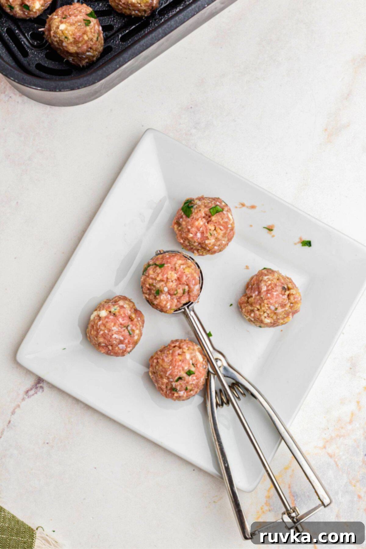 Crispy Air-Fried Greek Meatballs 5 Greek meatball mixture scooped into small meatballs on a square white plate.