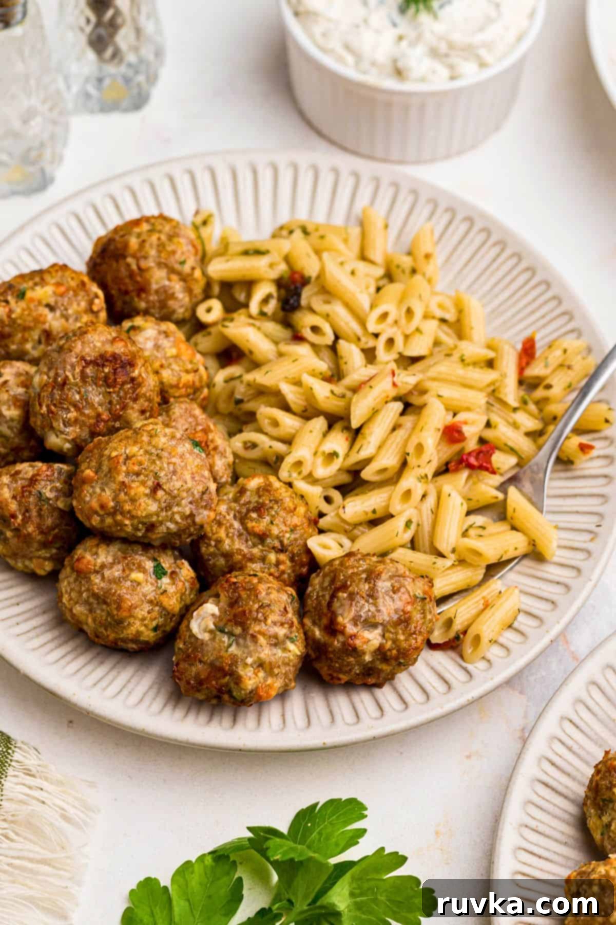 Crispy Air-Fried Greek Meatballs 7 Juicy, golden Greek meatballs with pasta on a small white plate.