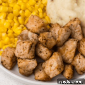 Crispy Air Fryer Pork Cubes 11 Close up of pork chop bites on a plate with corn and mashed potatoes.