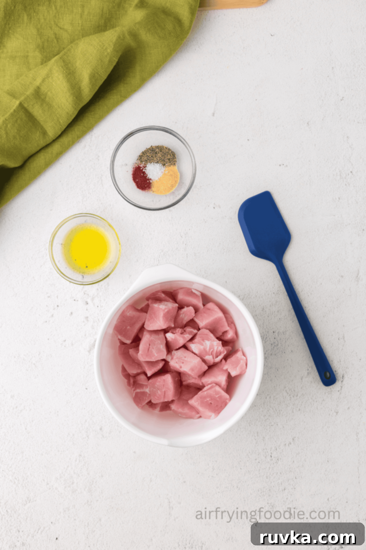 Crispy Air Fryer Pork Cubes 4 Pork chops cut into bites sized pieces in a medium mixing bowl.