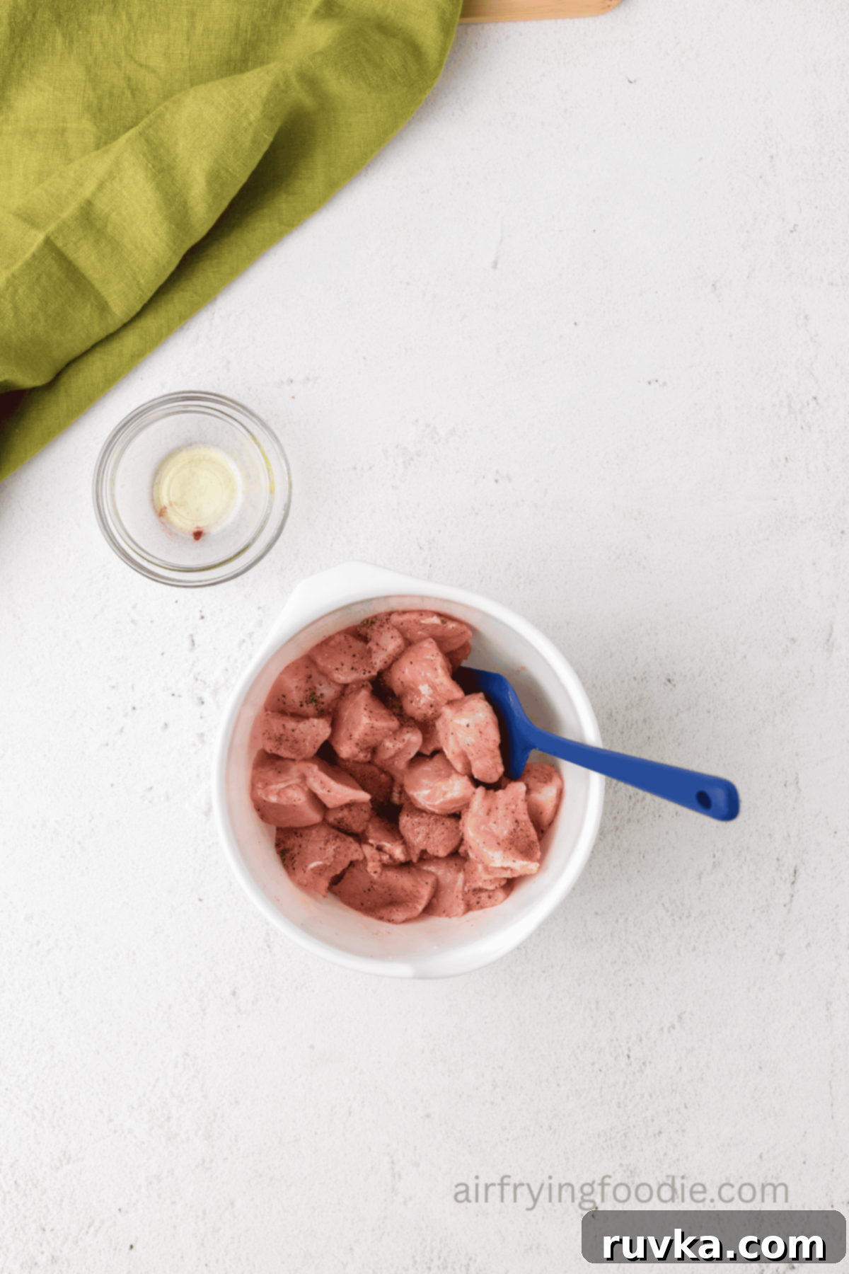 Crispy Air Fryer Pork Cubes 5 Pork chop bites mixed together in a bowl with olive oil and seasonings.