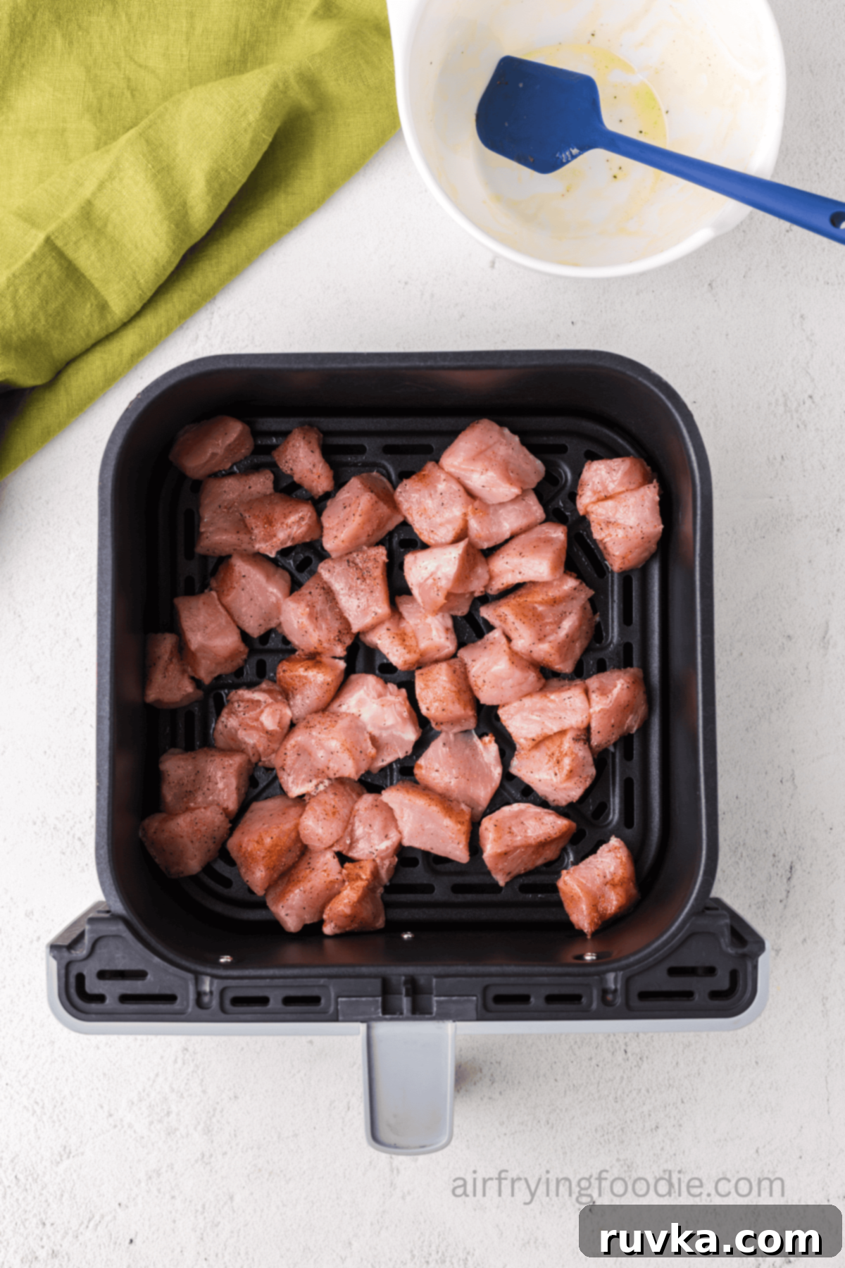 Crispy Air Fryer Pork Cubes 6 seasoned pork chop bites in the basket of the air fryer.