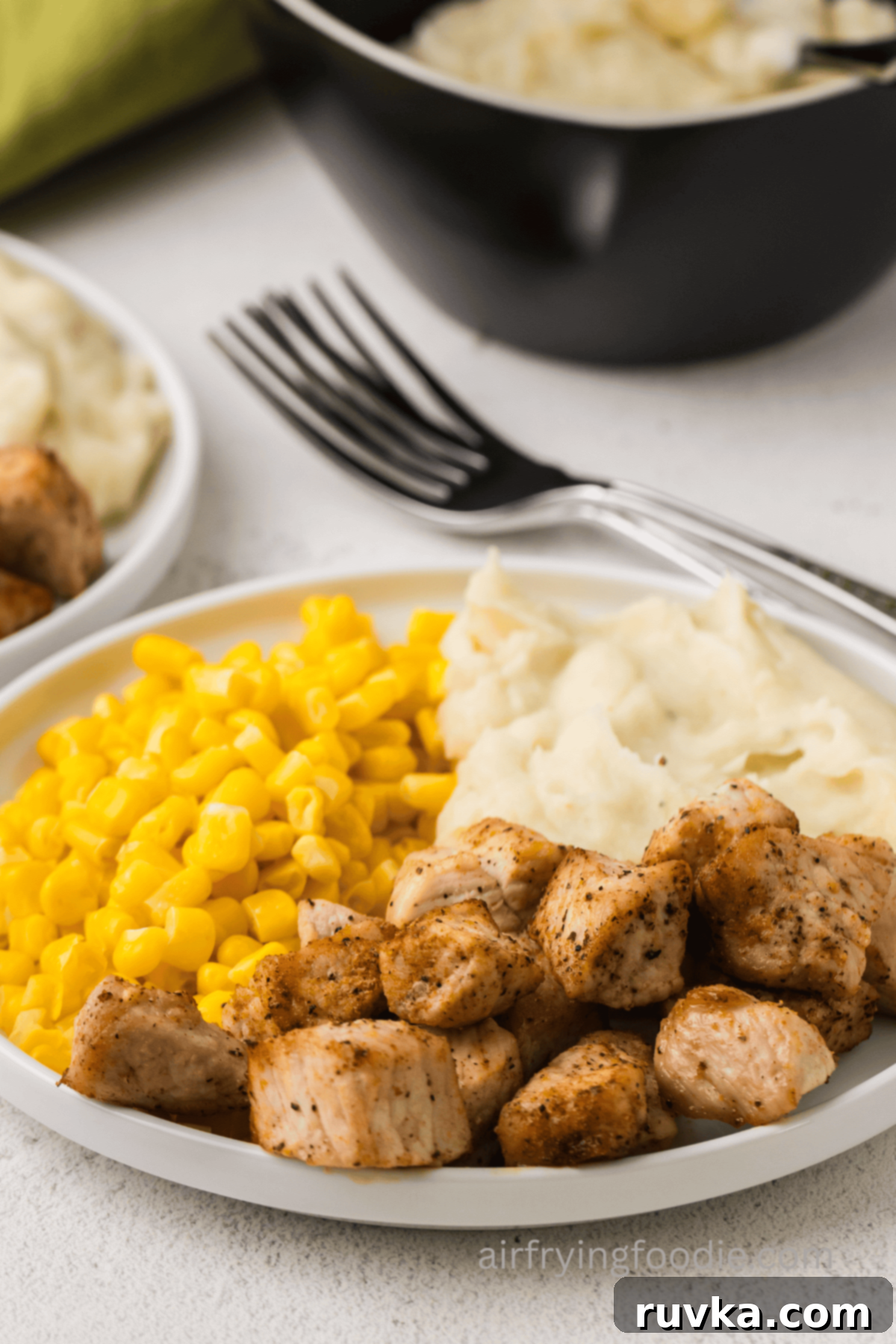 Crispy Air Fryer Pork Cubes 8 Plate of pork chop bites, corn, and mashed potatoes.